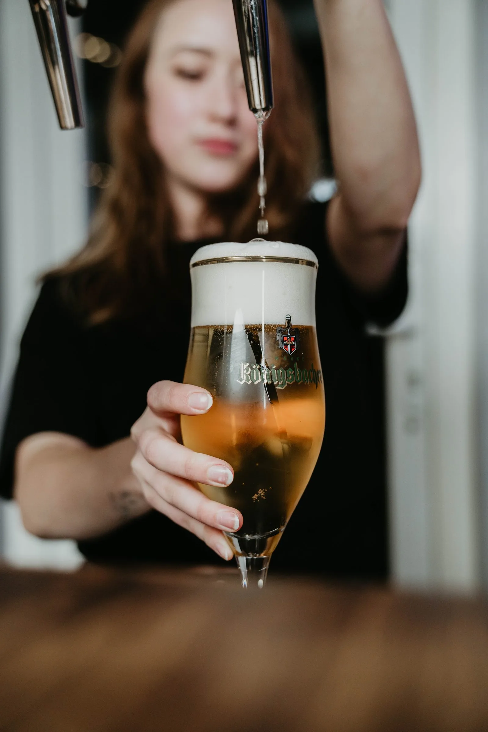 Eine Mitarbeiterin zapft ein frisches Bier.