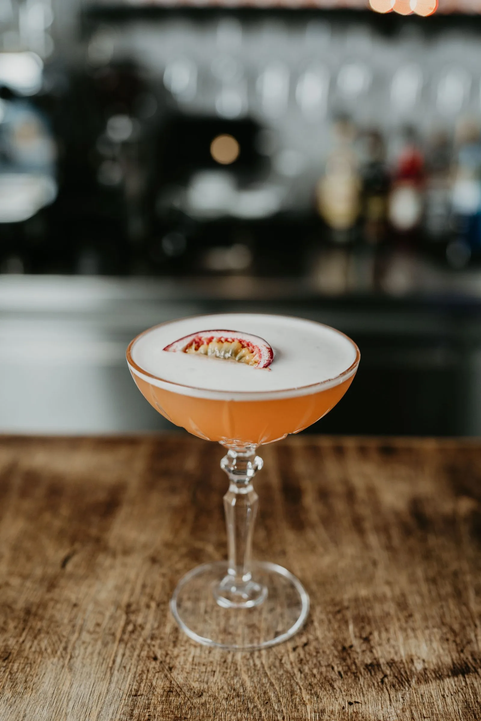 Ein Sour mit Schaumkrone und Maracuja-Hälfte im Stielglas.