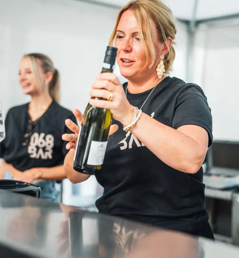 Eine Mitarbeiterin der 068 öffnet eine Flasche Wein an der Eventbar.