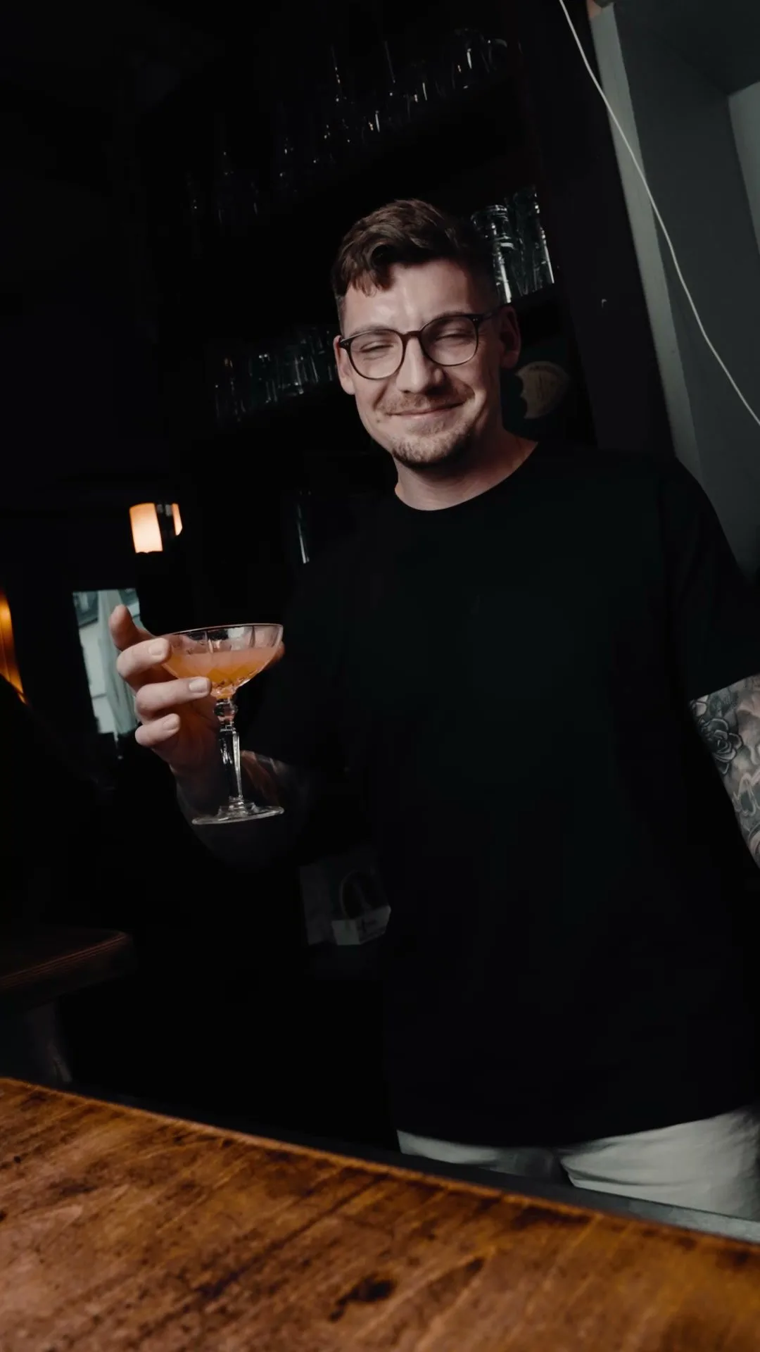 Ein Gast hält lächelnd einen Cocktail in die Kamera.