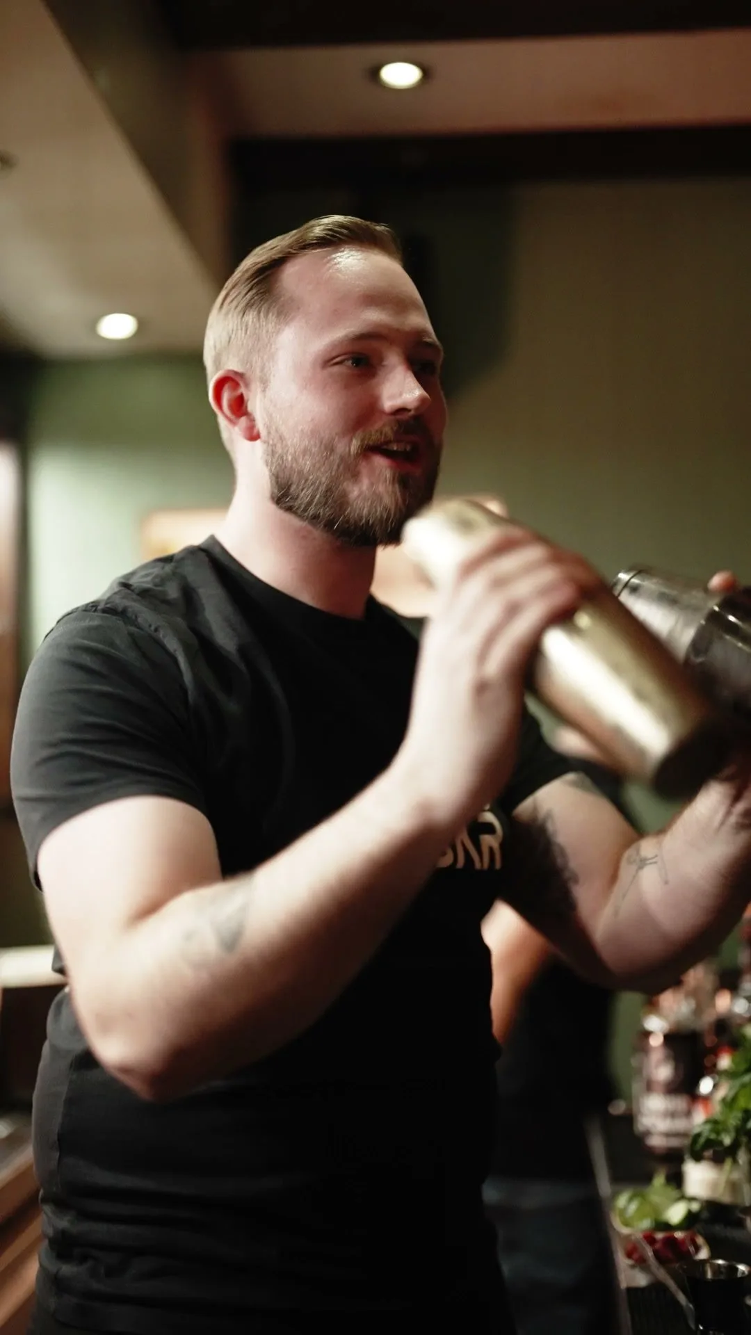 Ein Barkeeper der 068 schüttelt einen Cocktail am Tresen.