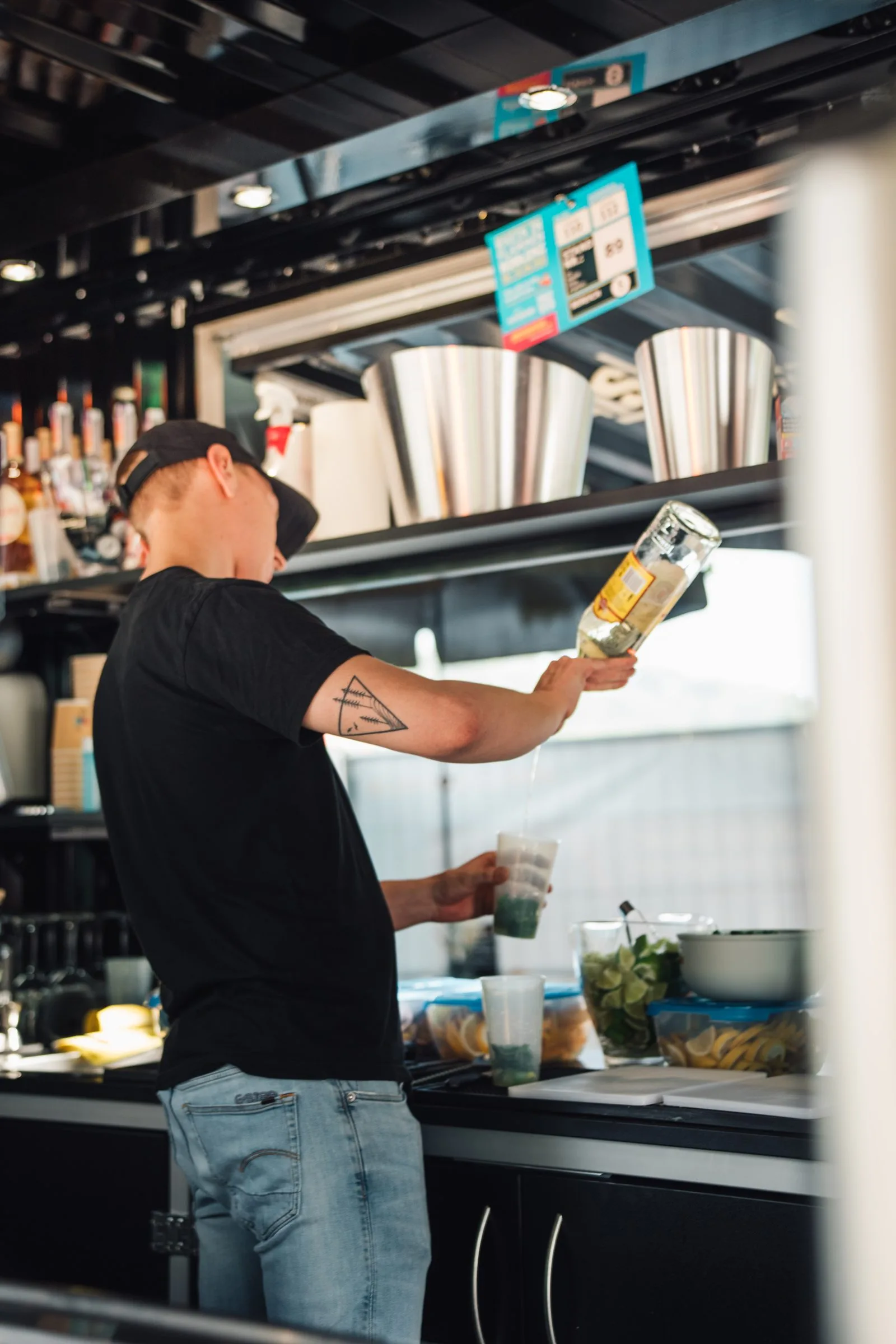 Ein Barkeeper greift an der Außenbar nach einer Flasche.