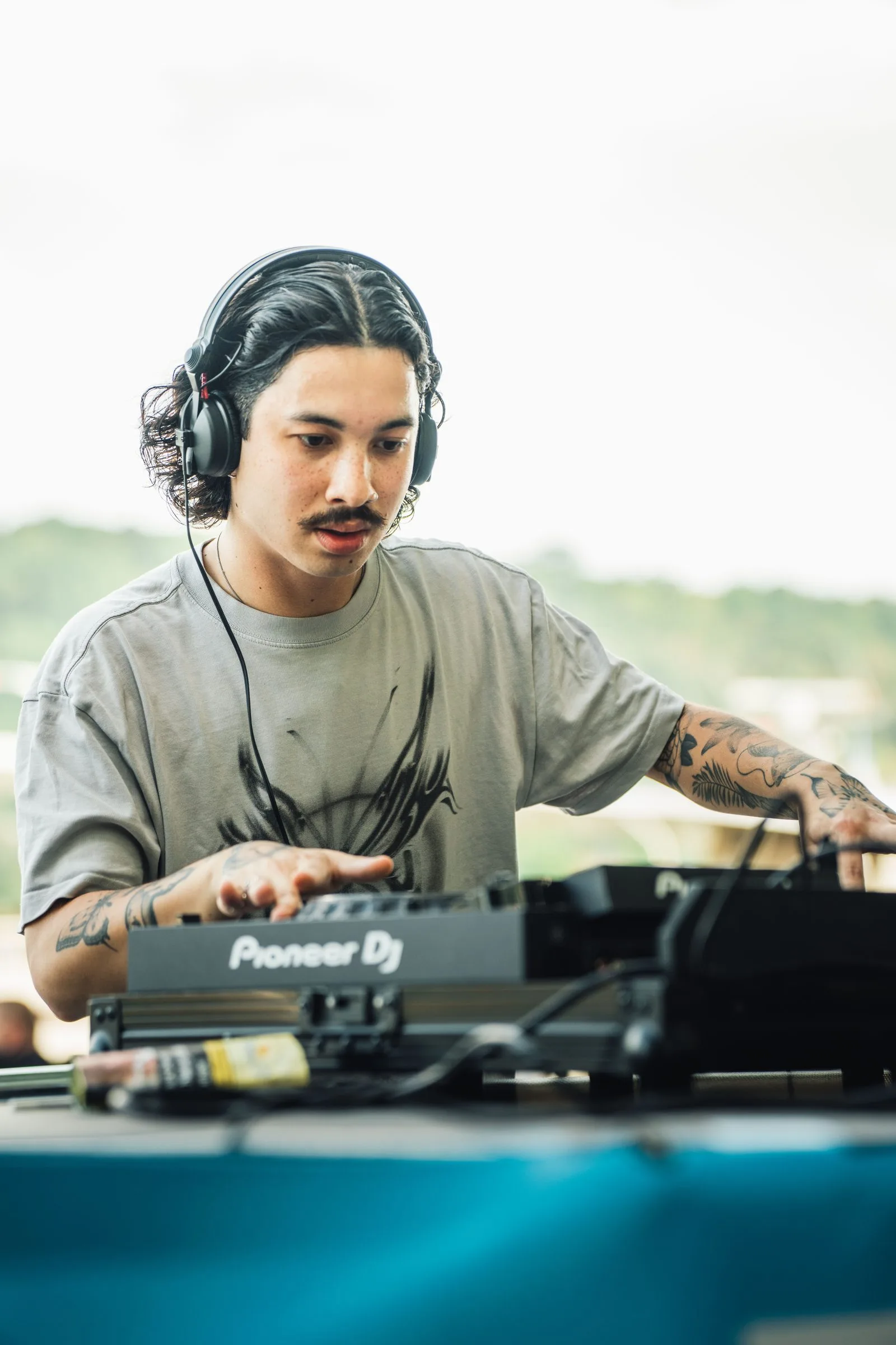 Ein DJ mit Kopfhörern legt am Rhein auf.