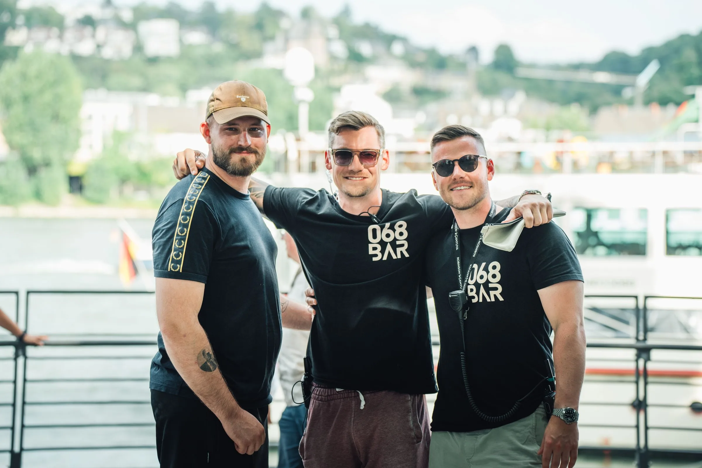 Die drei Inhaber der 068 Bar stehen gut gelaunt am Rheinufer.